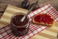 Plums with a jar of confiture and a toast bread &copy; freepik