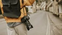 DSLR camera with strap hanging on photographer&rsquo;s shoulder &copy; Magnific