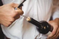 Mid section of bar tender opening a bottle of wine &copy; freepik