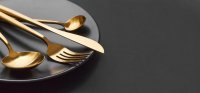 Gold cutlery set on black background © freepick